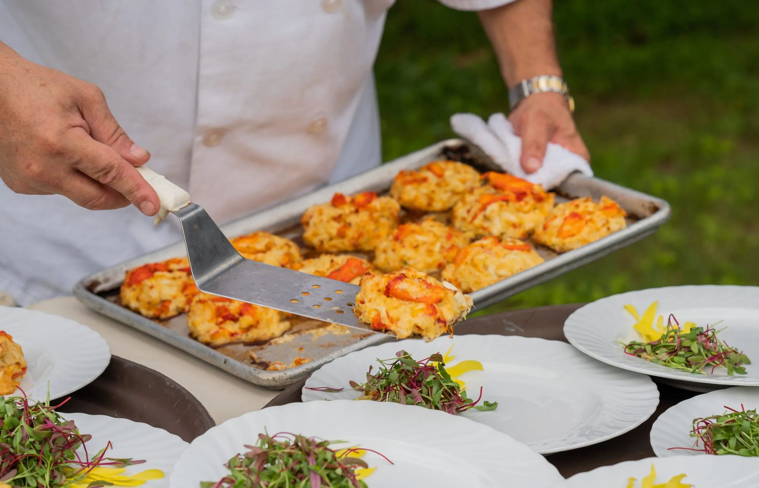Chef preparing crab cakes with garnish for a wedding dinner